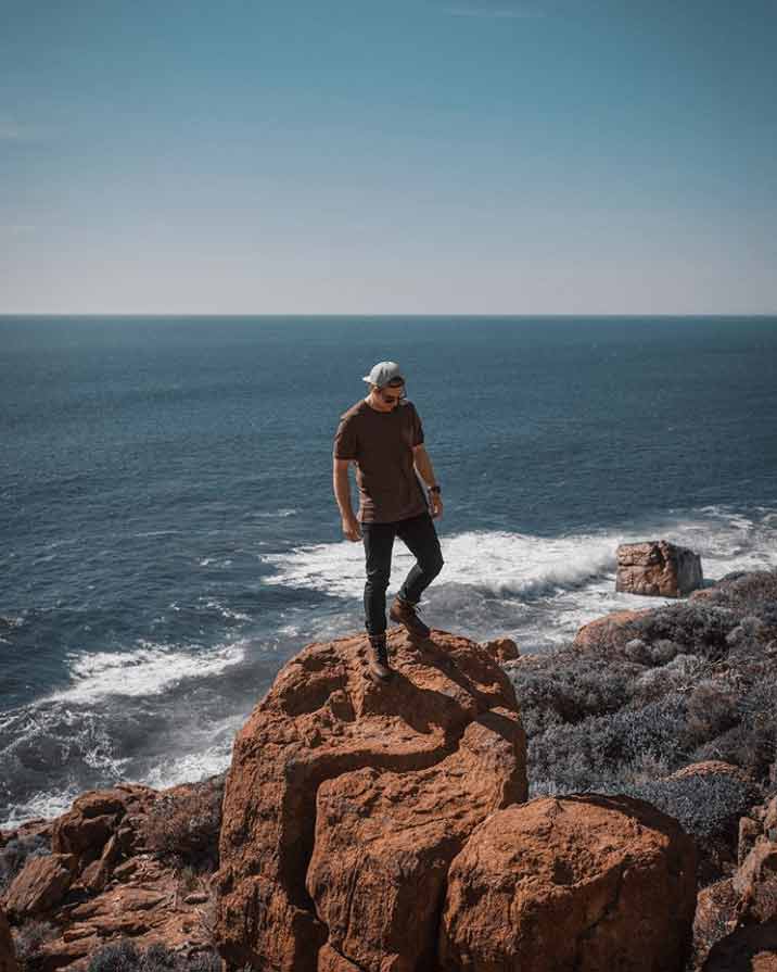 Model standing at the beach on the rocks, wearing Timberland boots